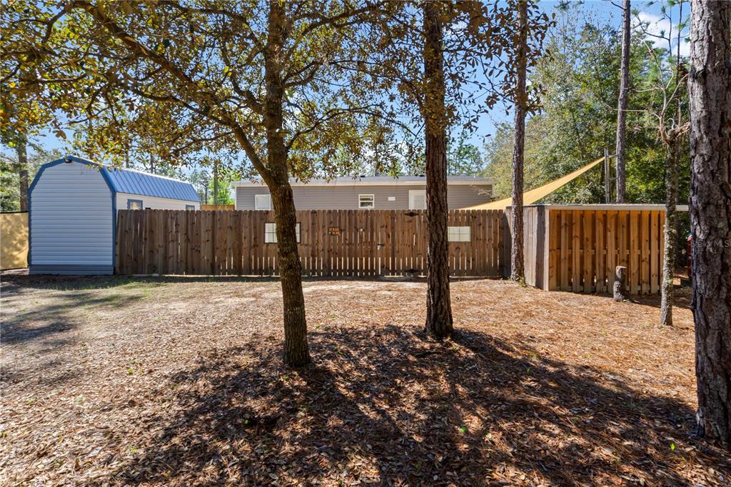 10811 Northeast 57th Street Bronson, FL 32621 - Photo 21 of 21 a view of a backyard with large trees and wooden fence