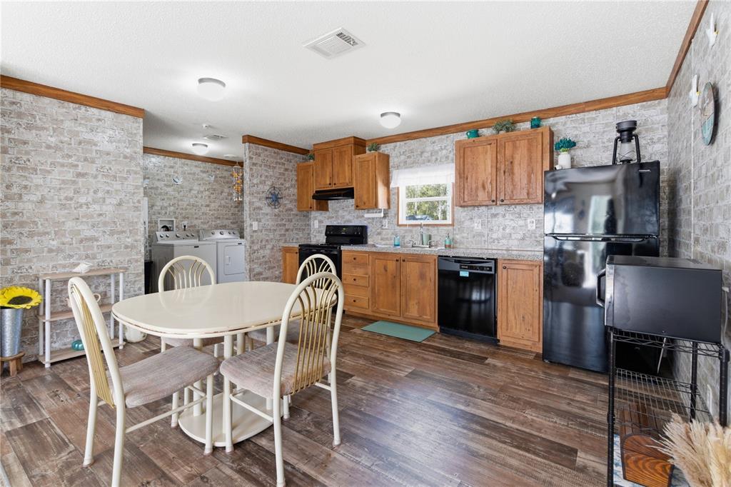 10811 Northeast 57th Street Bronson, FL 32621 - Photo 7 of 21 a kitchen with a table chairs a sink dishwasher refrigerator and cabinets