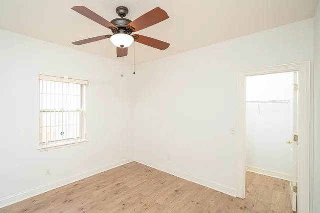 an empty room with windows and fan