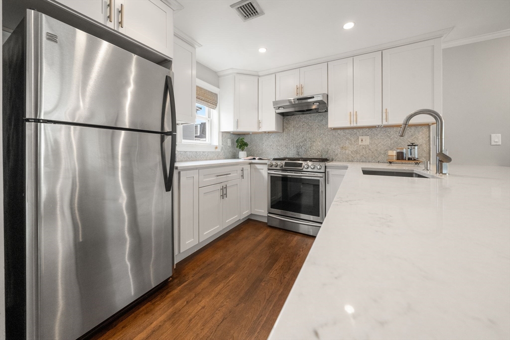 3 Glover Court, Unit 2 Boston, MA 02127 - Photo 3 of 27 a kitchen with stainless steel appliances granite countertop a refrigerator a sink dishwasher a stove top oven a refrigerator and white cabinets with wooden floor