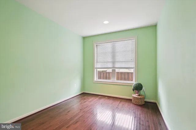 a view of an empty room with wooden floor and closet