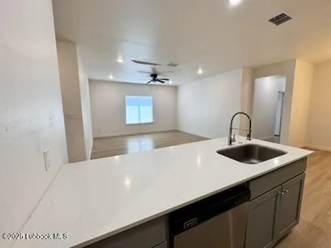 a kitchen with stainless steel appliances a sink dishwasher a refrigerator a microwave oven with cabinets and wooden floor