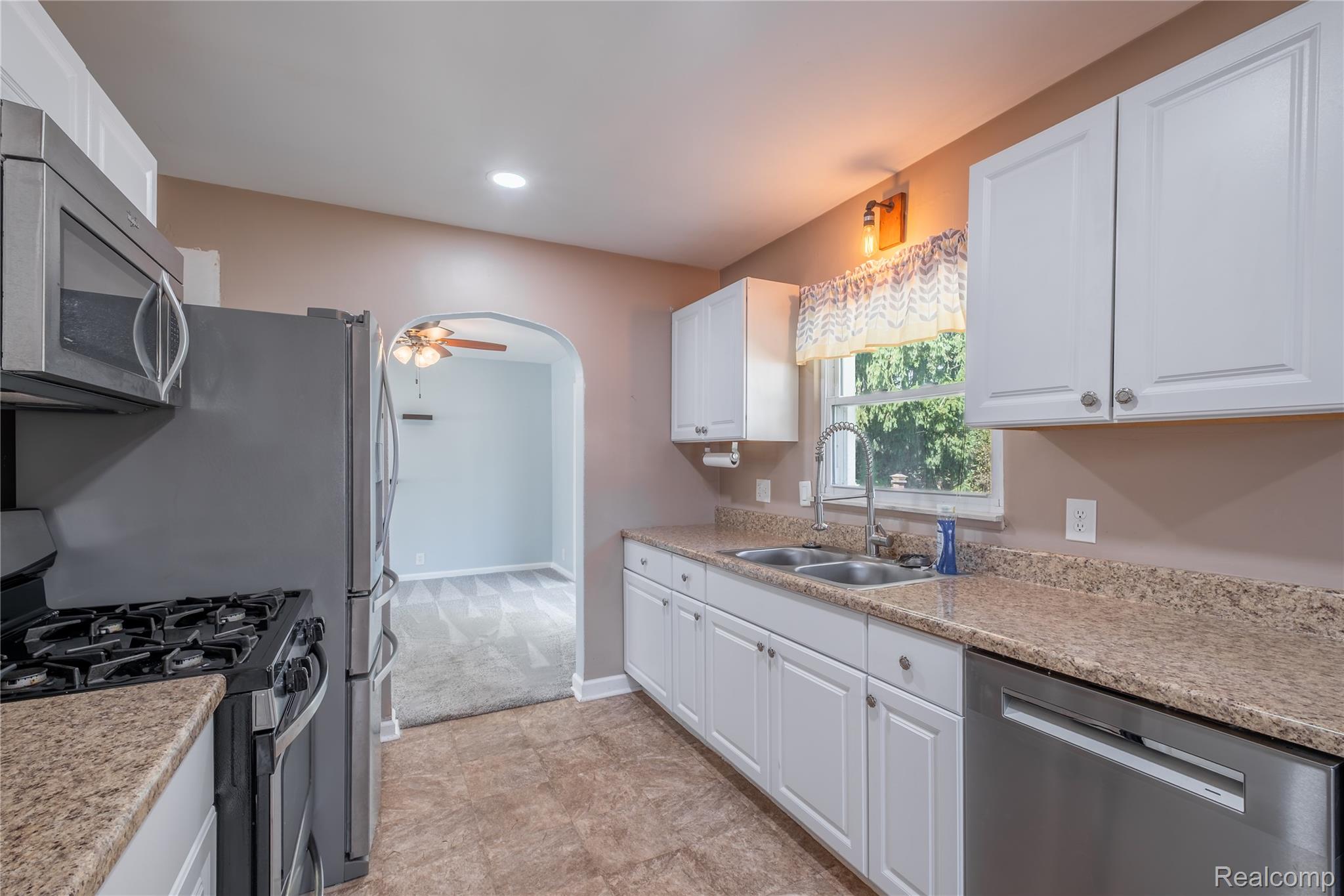 2432 Farrand Road Clio, MI 48420 - Photo 7 of 27 Kitchen featuring white cabinetry, light-toned countertops, a stainless steel double sink, and a stainless steel dishwasher