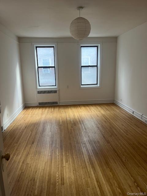 110-20 73rd Road, Unit 3E Queens, NY 11375 - Photo 7 of 10 an empty room with wooden floor chandelier and windows