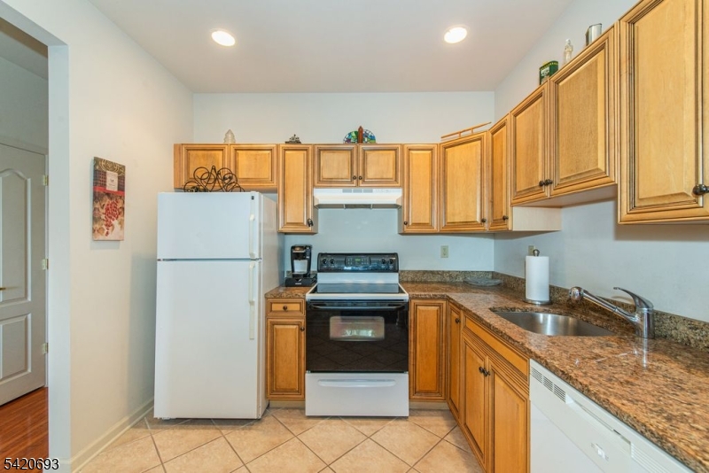 375 Rifle Camp Road, Unit 403 Woodland Park, NJ 07424 - Photo 21 of 24 a kitchen with stainless steel appliances granite countertop a refrigerator a stove and a sink