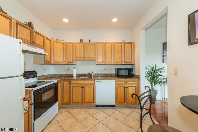 375 Rifle Camp Road, Unit 403 Woodland Park, NJ 07424 - Photo 5 of 24 a kitchen with a white cabinets and chairs