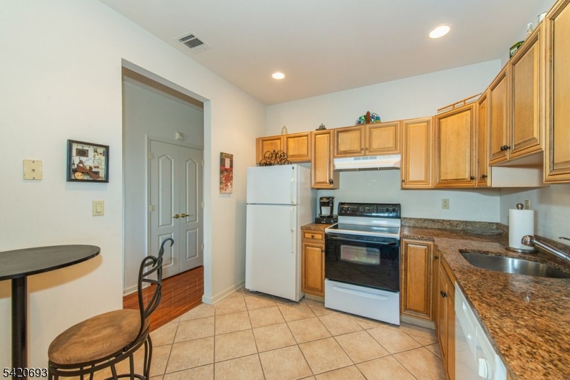 375 Rifle Camp Road, Unit 403 Woodland Park, NJ 07424 - Photo 8 of 24 a kitchen with stainless steel appliances granite countertop a refrigerator and a stove top oven