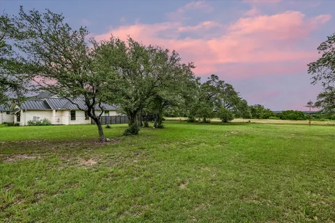 a view of a green field with trees in the background