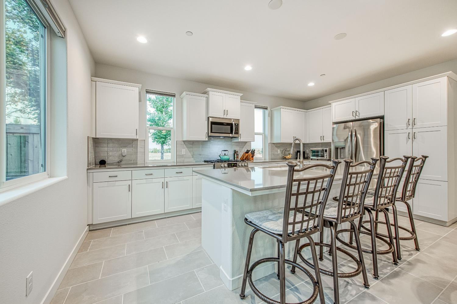 849 Livio Way Madera, CA 93636 - Photo 19 of 74 a kitchen with stainless steel appliances kitchen island granite countertop a stove a sink a refrigerator with a dining table and chairs
