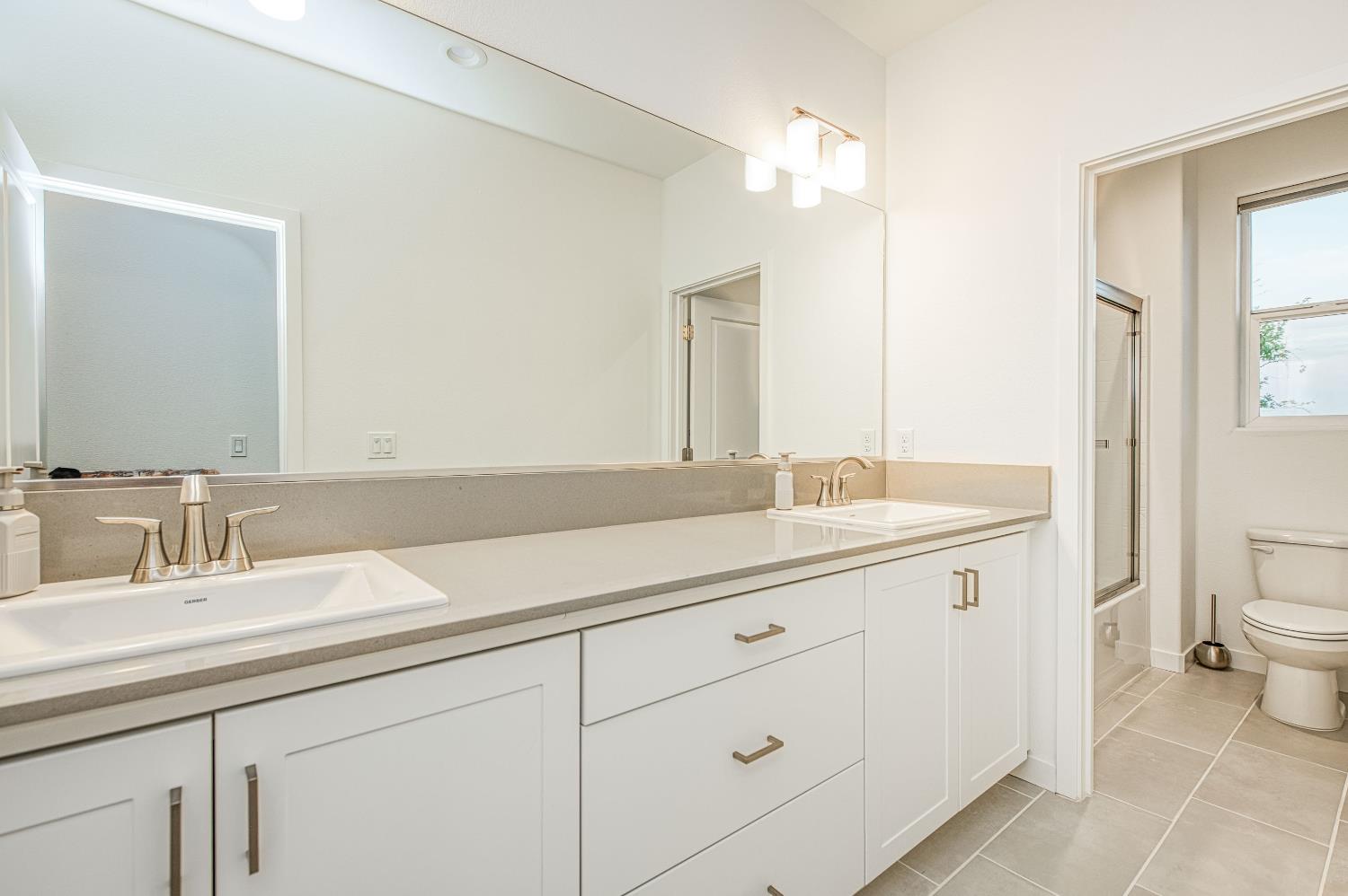 849 Livio Way Madera, CA 93636 - Photo 34 of 74 a bathroom with a granite countertop sink a toilet and a mirror