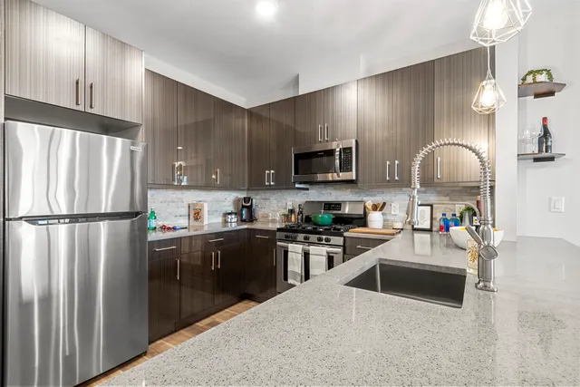 a kitchen with stainless steel appliances granite countertop a refrigerator sink stove microwave and cabinets