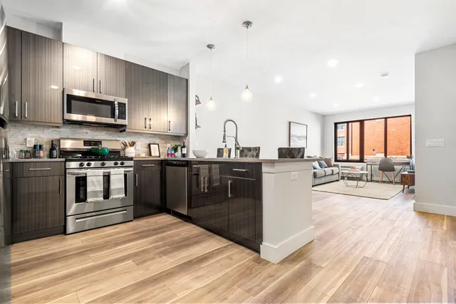 a kitchen with stainless steel appliances kitchen island granite countertop a stove top oven a sink a counter space and cabinets