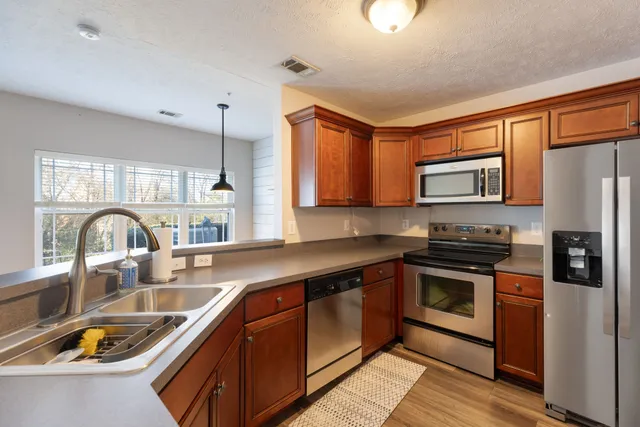 a kitchen with stainless steel appliances granite countertop a sink stove refrigerator and cabinets
