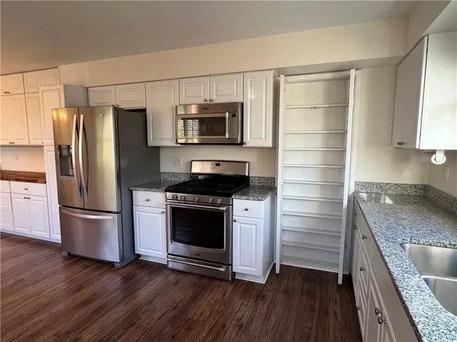 a kitchen with stainless steel appliances granite countertop a refrigerator a stove and a wooden floors