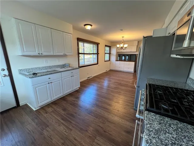 a kitchen with stainless steel appliances granite countertop sink stove a dining table and chairs