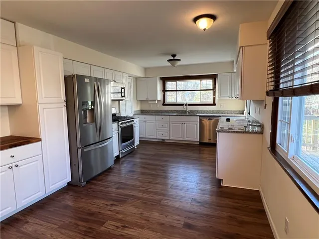 a kitchen with granite countertop white cabinets and a window
