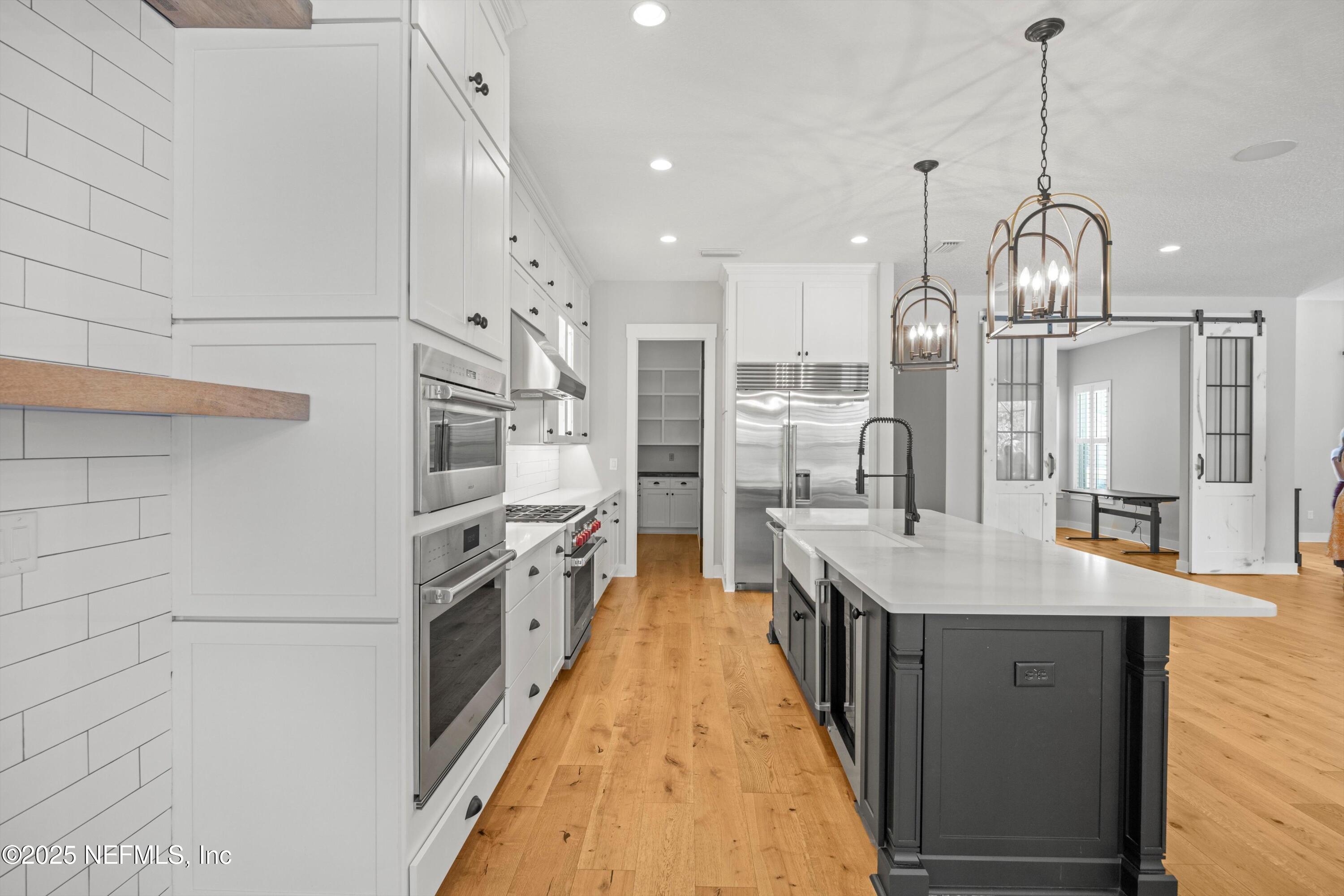 86 Sunset Ridge Court St. Johns, FL 32259 - Photo 16 of 66 a large kitchen with granite countertop a large kitchen island white cabinetry and stainless steel appliances