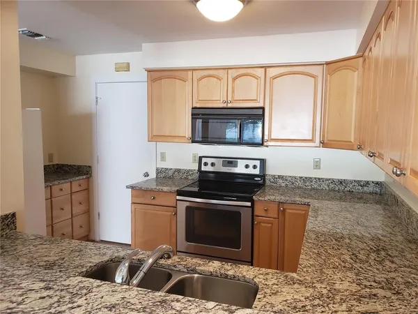a kitchen with stainless steel appliances granite countertop a stove a sink and a microwave