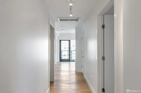 a view of a hallway with wooden floor and closet