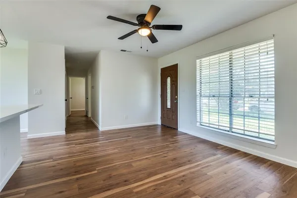 a view of an empty room with wooden floor and a window