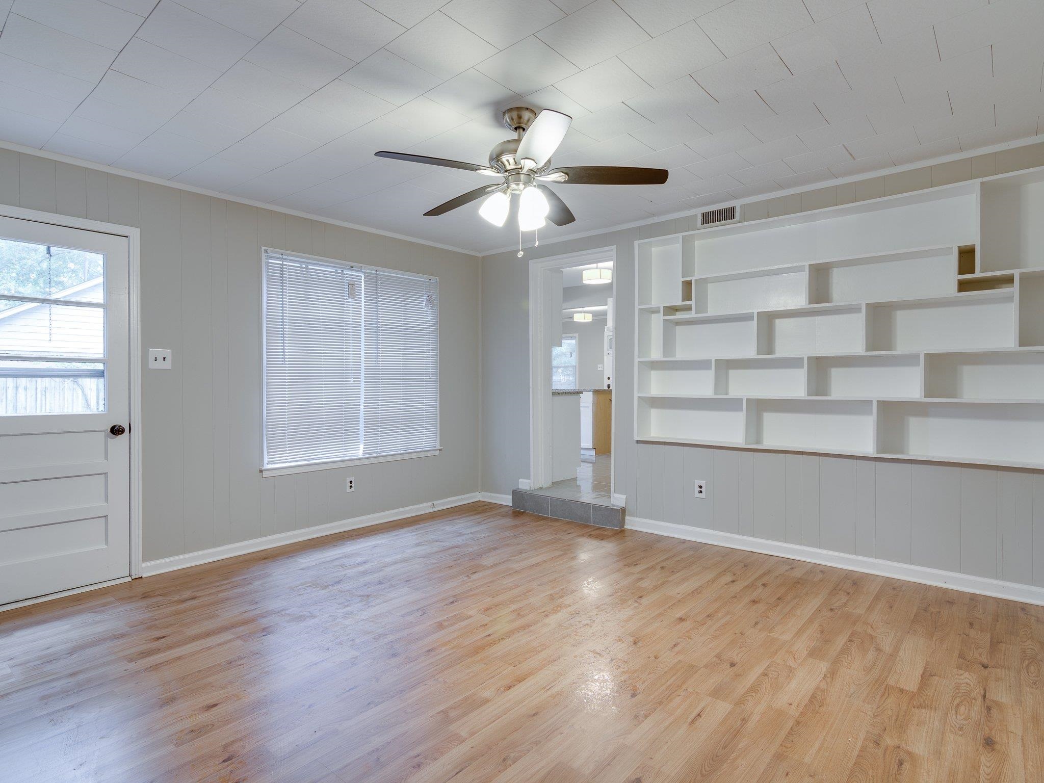 450 Homeville Road Collierville, TN 38017 - Photo 8 of 17 Unfurnished living room featuring built in shelves, a ceiling fan, light wood-style flooring, ornamental molding, and wooden walls
