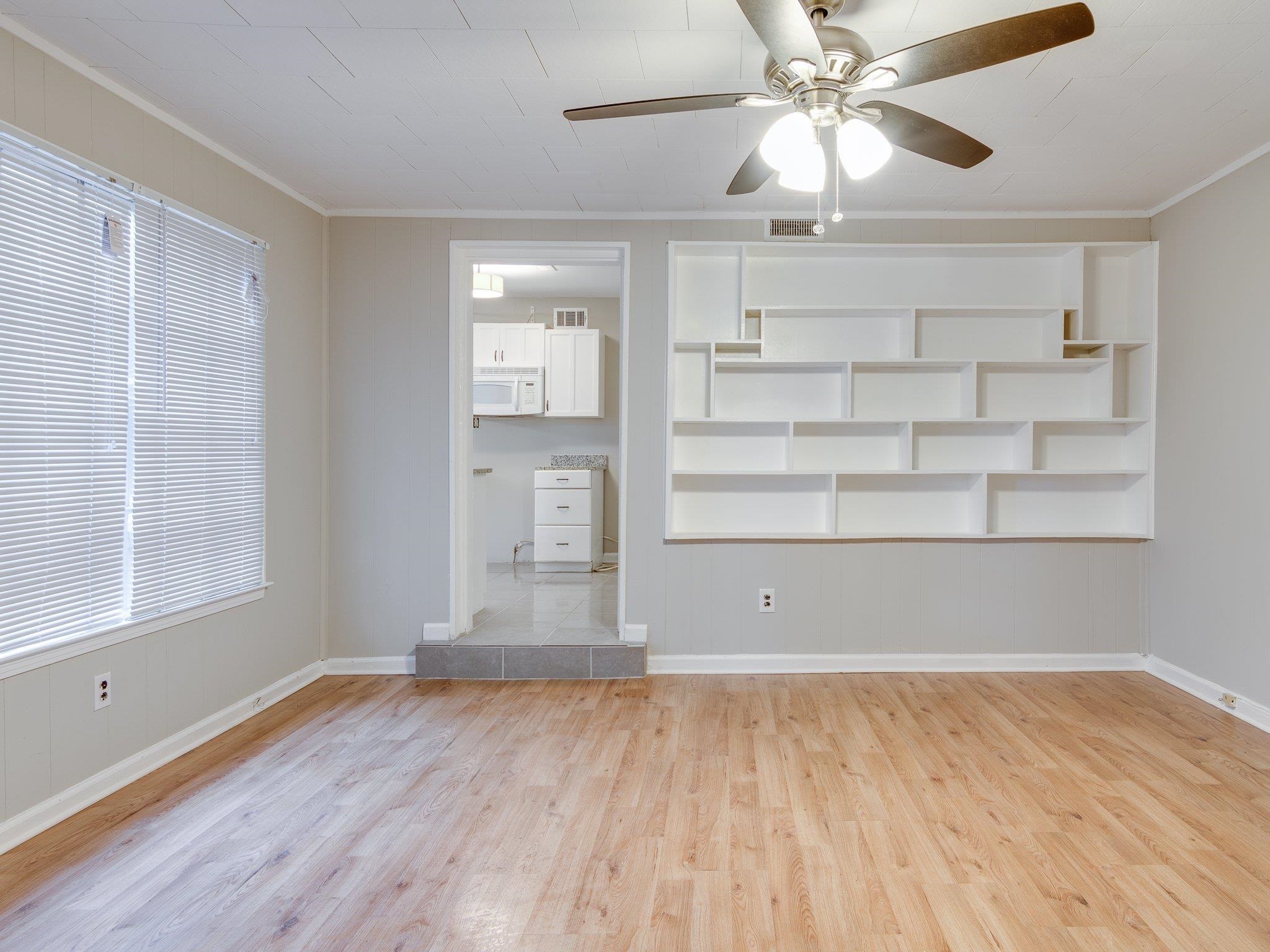 450 Homeville Road Collierville, TN 38017 - Photo 9 of 17 Unfurnished living room with ceiling fan, crown molding, light wood-style floors, and built in shelves