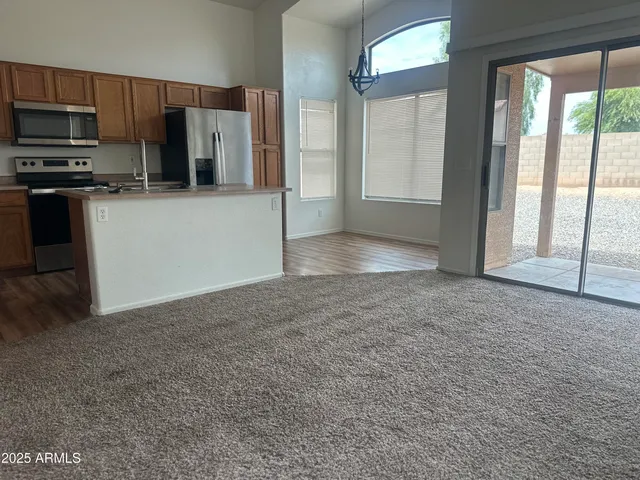 a view of a kitchen with stainless steel appliances wooden floor and large window