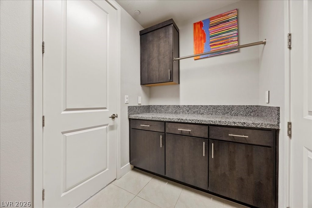 4262 Swift Street Las Vegas, NV 89135 - Photo 36 of 75 Kitchen with dark brown cabinetry, light stone countertops, and light tile patterned flooring