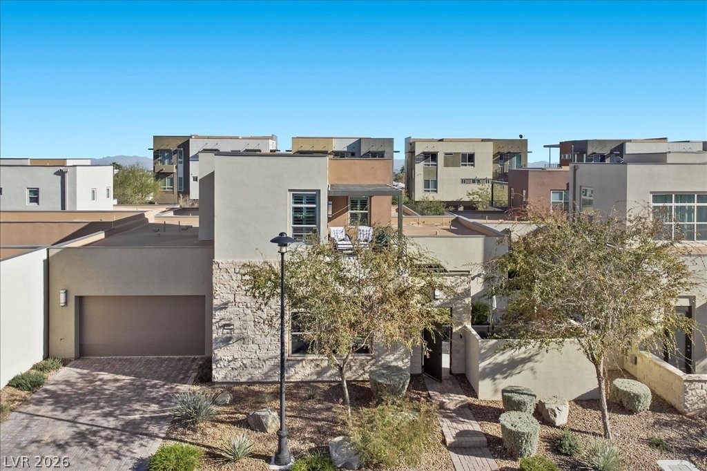 4262 Swift Street Las Vegas, NV 89135 - Photo 51 of 75 Back of house featuring a residential view, driveway, a garage, and stucco siding