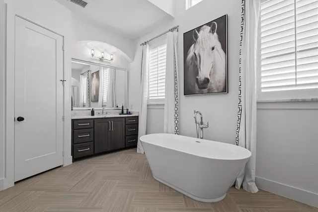a bathroom with a tub a double vanity sink and mirror