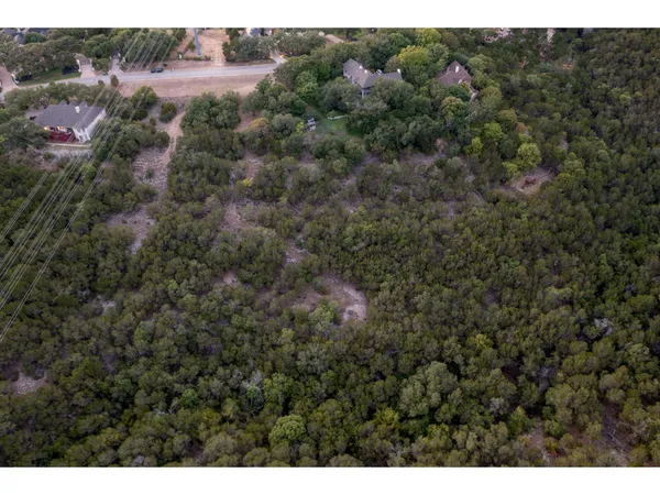 an aerial view of residential houses with outdoor space and trees