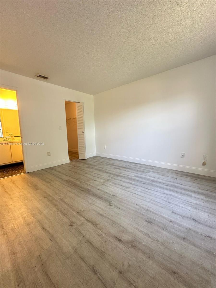 861 Northeast 209th Terrace, Unit 203 Miami, FL 33179 - Photo 11 of 16 an empty room with wooden floor and windows