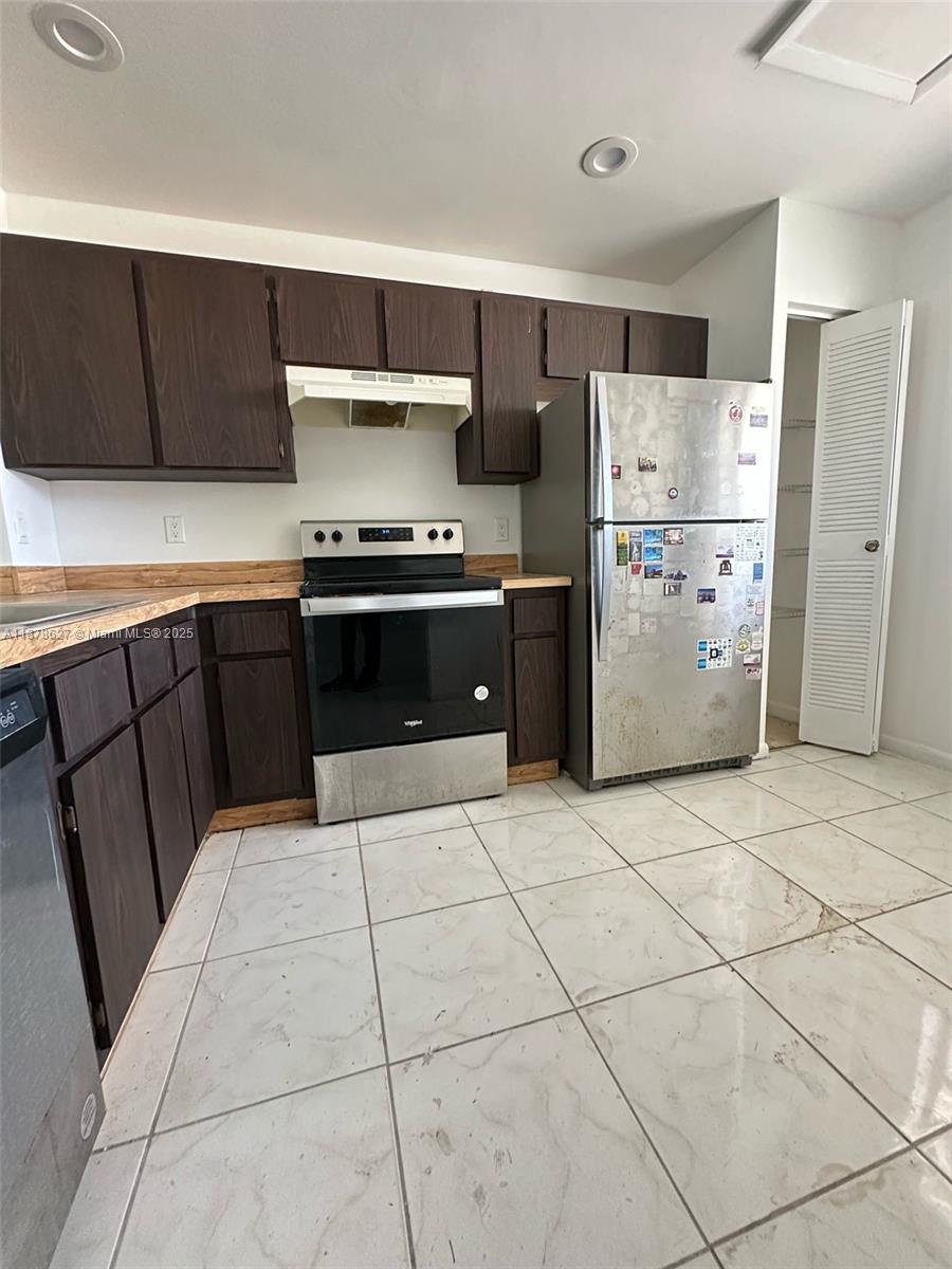 861 Northeast 209th Terrace, Unit 203 Miami, FL 33179 - Photo 2 of 16 a kitchen with a refrigerator a stove top oven and cabinets