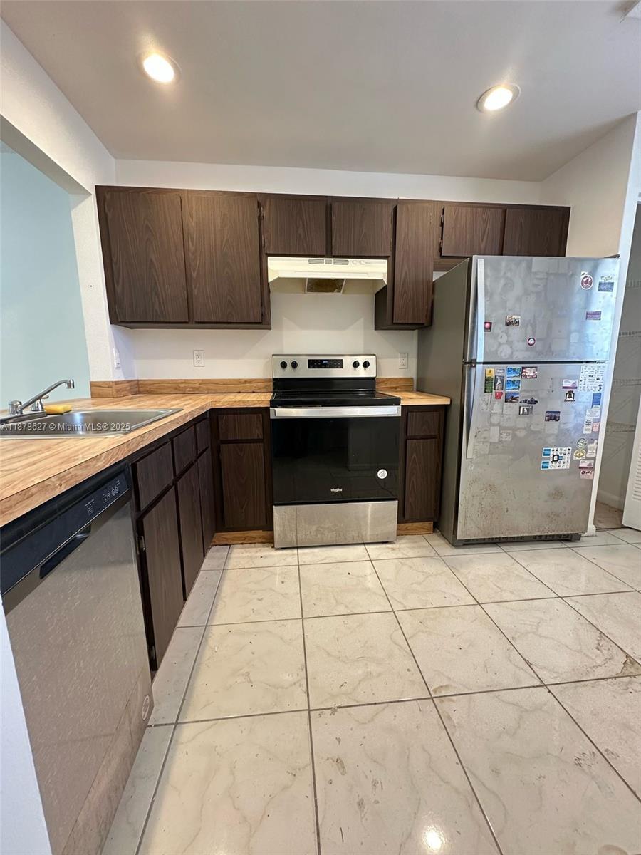 861 Northeast 209th Terrace, Unit 203 Miami, FL 33179 - Photo 3 of 16 a kitchen with stainless steel appliances a stove a sink and a refrigerator
