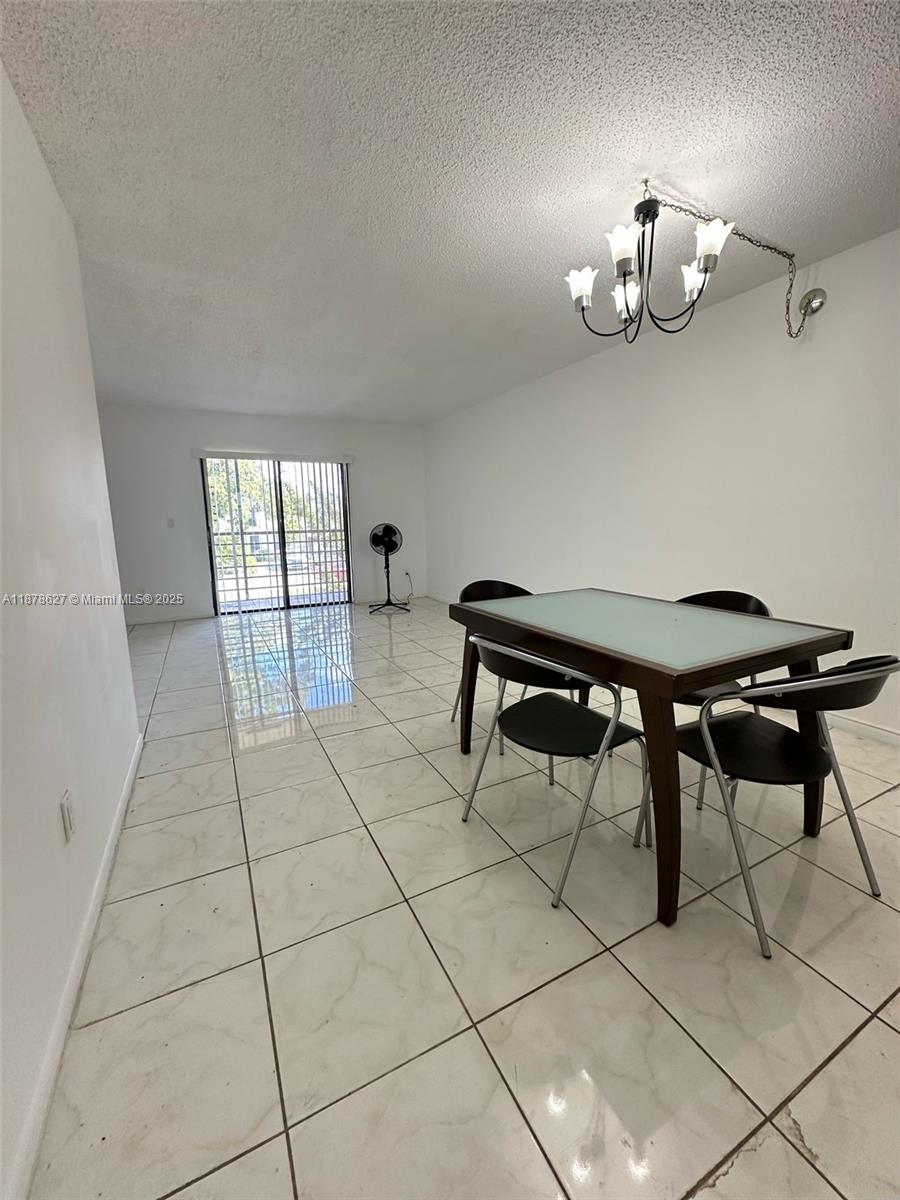 861 Northeast 209th Terrace, Unit 203 Miami, FL 33179 - Photo 6 of 16 a view of a dining room with furniture and chandelier