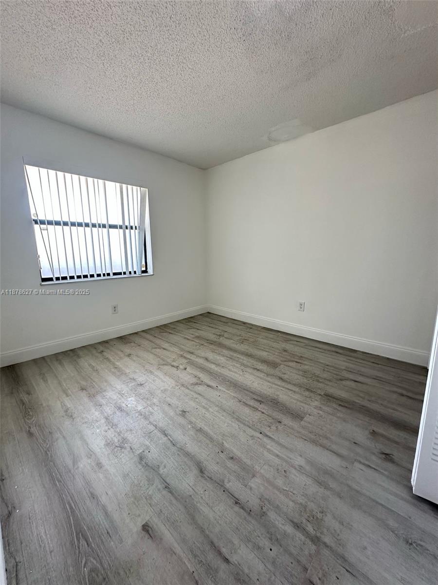 861 Northeast 209th Terrace, Unit 203 Miami, FL 33179 - Photo 8 of 16 an empty room with wooden floor and windows