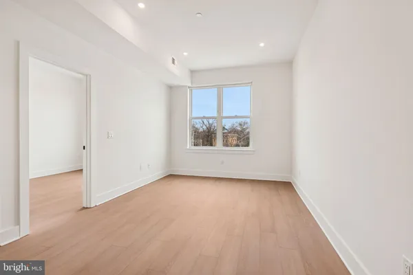 a view of an empty room with a window and wooden floor