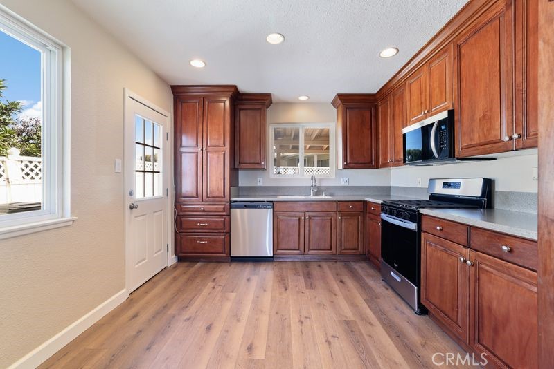 14802 Springford Drive La Mirada, CA 90638 - Photo 10 of 26 a kitchen with stainless steel appliances granite countertop wooden cabinets a stove top oven a sink and dishwasher with wooden floor