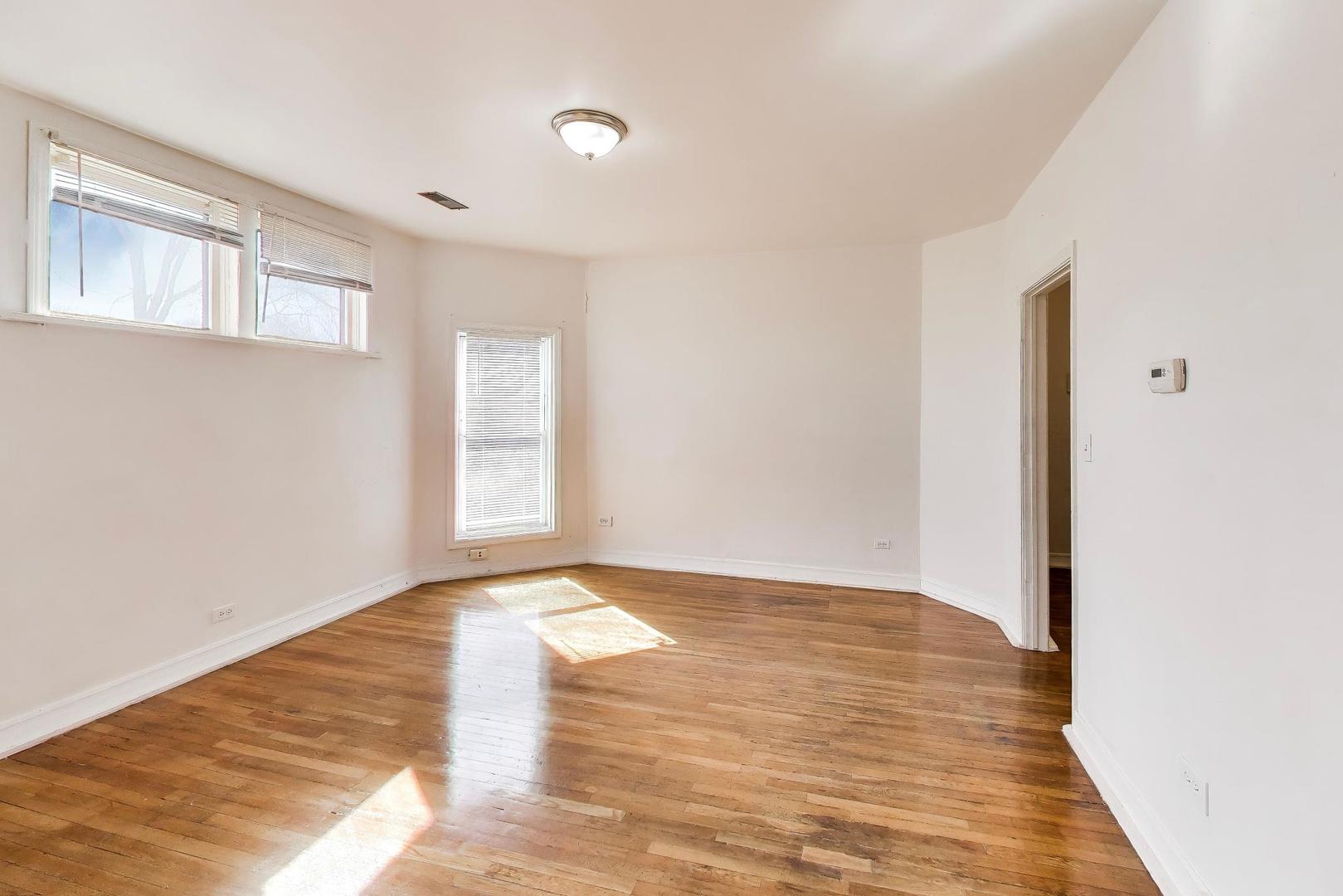 6853 South Perry Avenue Chicago, IL 60621 - Photo 13 of 28 a view of an empty room with window and wooden floor