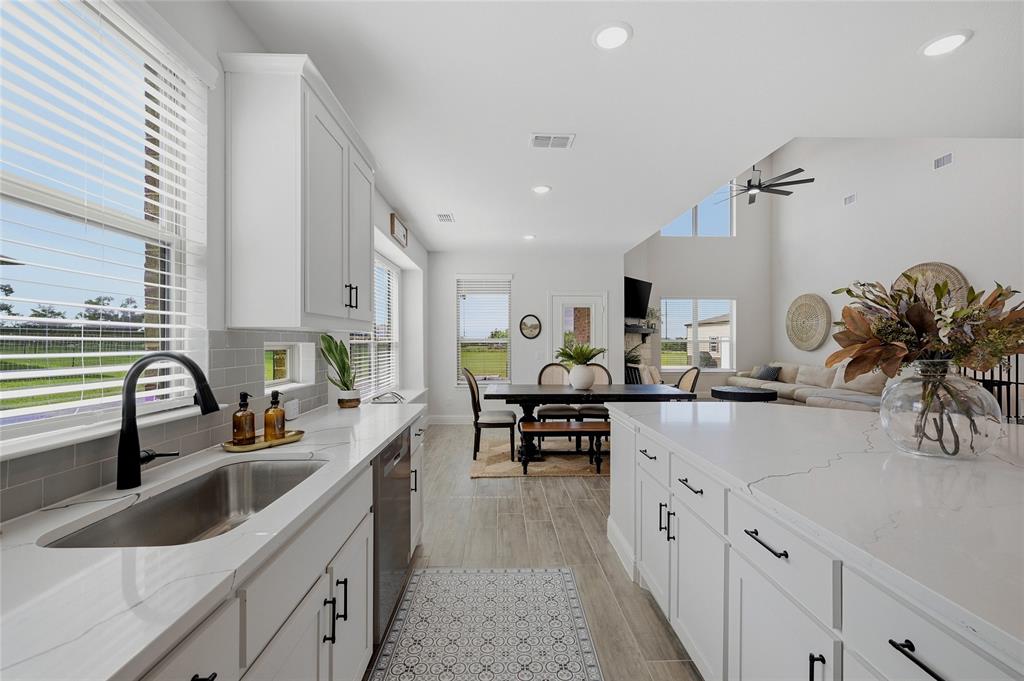 864 Shadow Valley Road Whitesboro, TX 76273 - Photo 16 of 40 Modern kitchen featuring white shaker cabinetry, white countertops, a stainless steel undermount sink with a black gooseneck faucet, and light grey subway tile backsplash