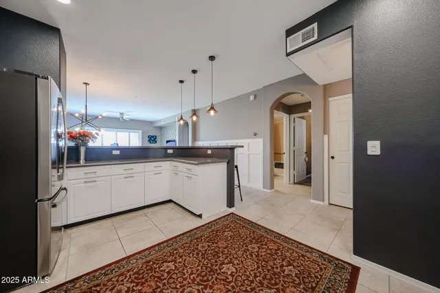a large white kitchen with a refrigerator a sink dishwasher and white cabinets with wooden floor