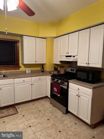 a kitchen with granite countertop a stove a sink and a microwave