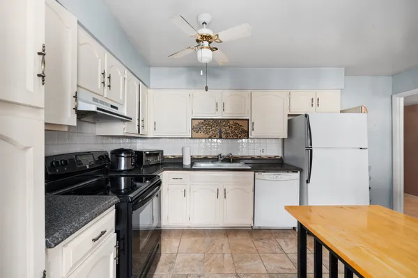 a kitchen with granite countertop a sink a stove a refrigerator and cabinets