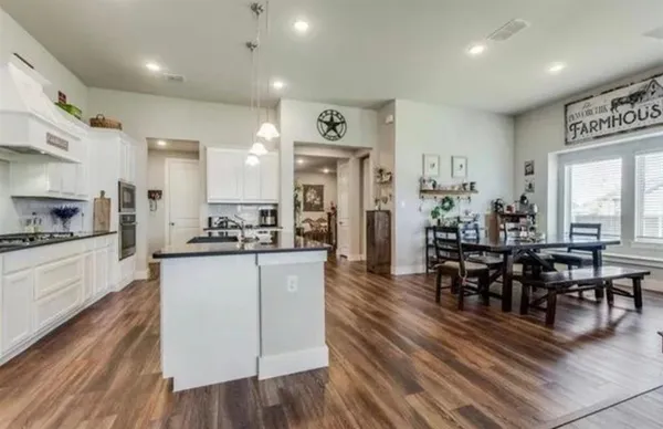 a large kitchen with cabinets chairs and wooden floor