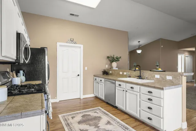 a kitchen with stainless steel appliances granite countertop a sink cabinets and wooden floor