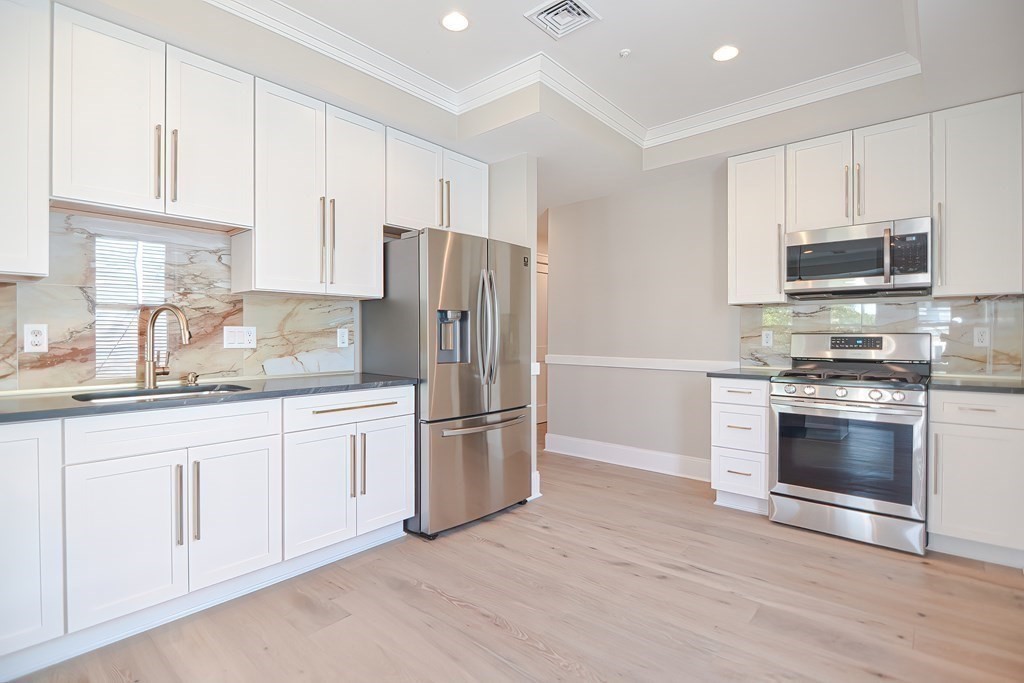 69 Falcon Street, Unit 2 Boston, MA 02128 - Photo 2 of 13 a kitchen with granite countertop white cabinets and stainless steel appliances