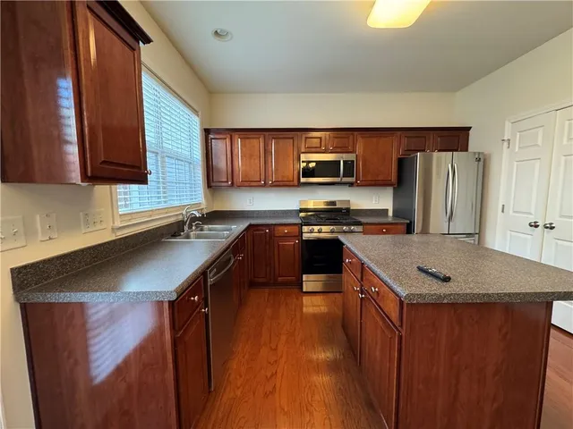 a kitchen with stainless steel appliances granite countertop a sink a stove a refrigerator a sink a microwave and island