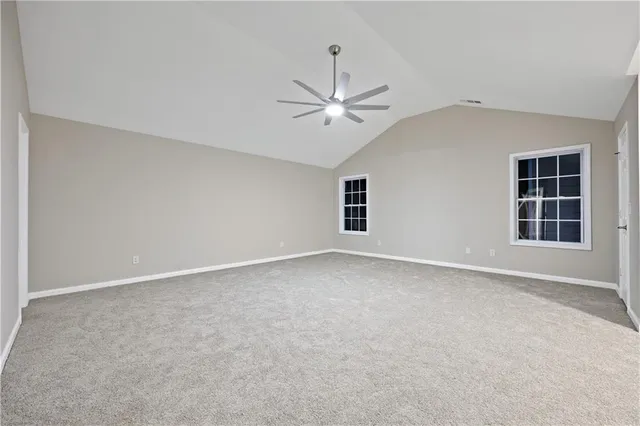 an empty room with windows and ceiling fan