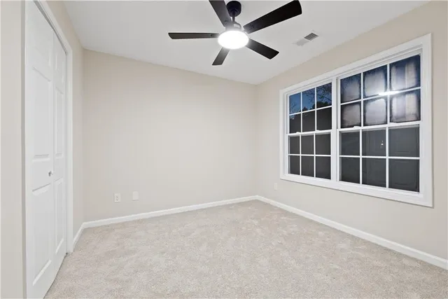 an empty room with a window and a ceiling fan