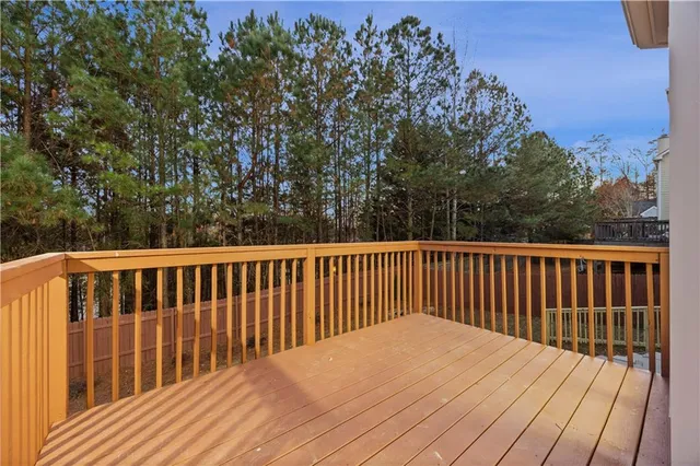 a balcony with wooden floor and trees in the back